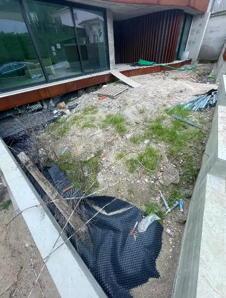 Jardim de moradia contemporânea com relva sintética e pátio interior — durante a obra