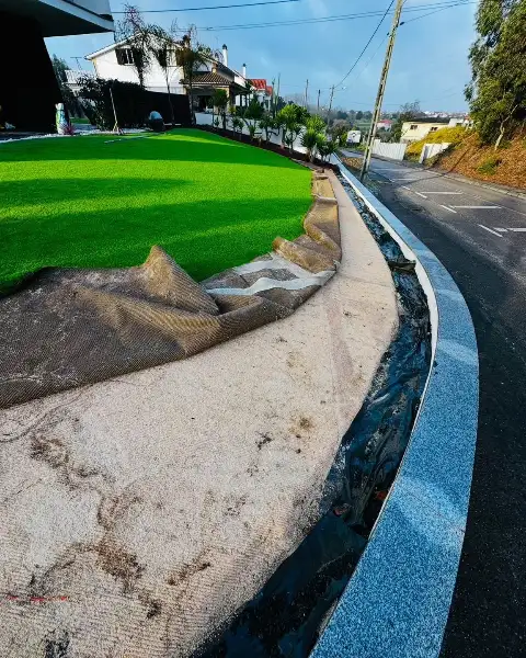 Jardim de moradia com palmeiras, seixo branco e relva sintética — durante a obra