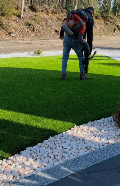Jardim de moradia com palmeiras, seixo branco e relva sintética — durante a obra