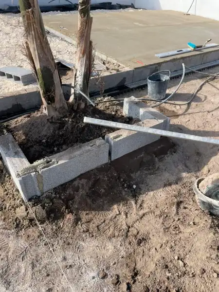Jardim amplo com relva sintética, caminhos em lajes e zona de fogueira — durante a obra