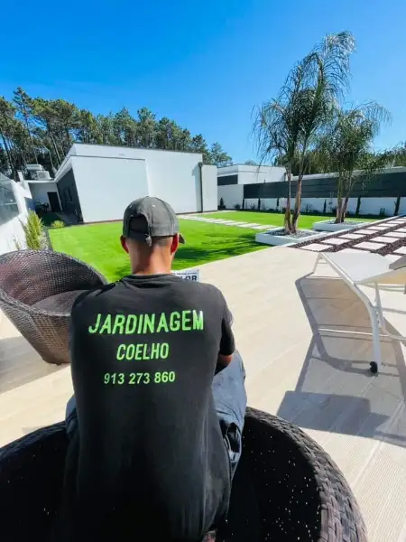 Jardim amplo com relva sintética, caminhos em lajes e zona de fogueira — resultado final