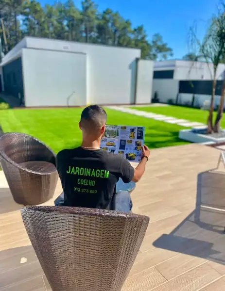 Jardim amplo com relva sintética, caminhos em lajes e zona de fogueira — resultado final